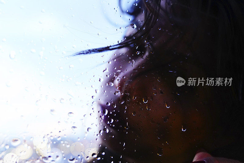 一个悲伤的女人在雨天站在窗前