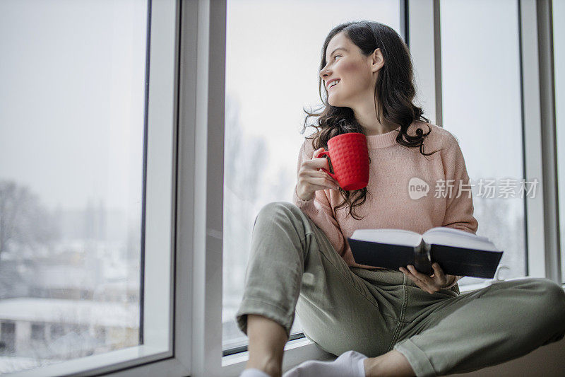 年轻快乐的女人正在喝咖啡休息，在家看书