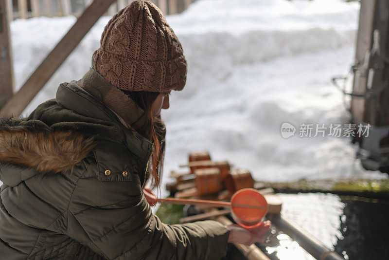 美丽的年轻女子洗手在chozuya在冬天