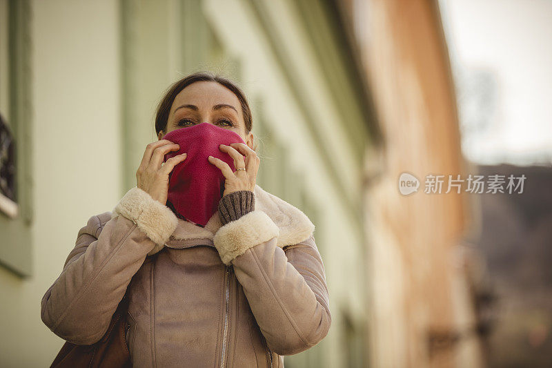 一个成熟的女人在城市的街道上走着，一边调整着她的颈圈