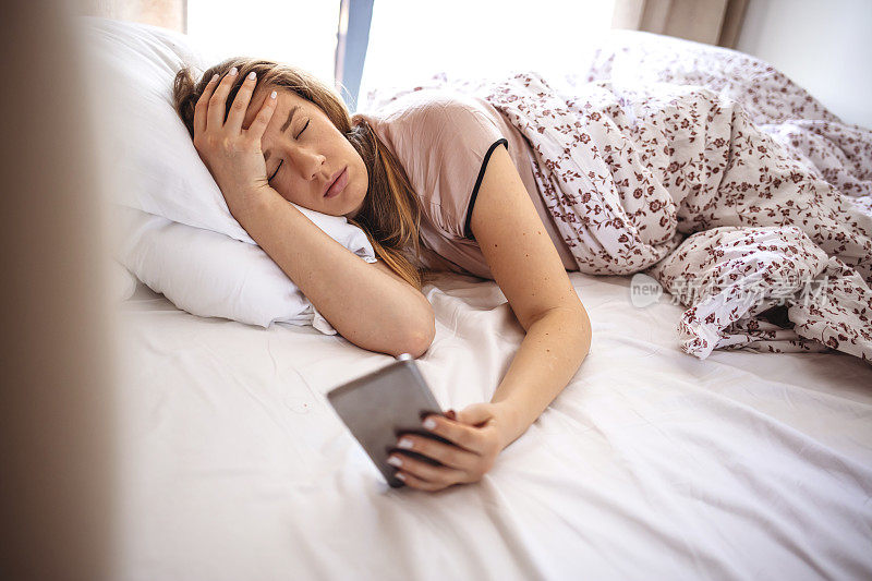 早晨，一名女子躺在床上，试图关掉手机的闹铃