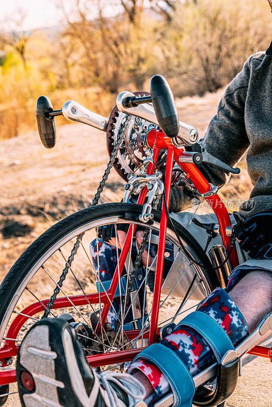 齿轮的特写镜头与一个男人的矫形腿支架适应运动的红色自行车