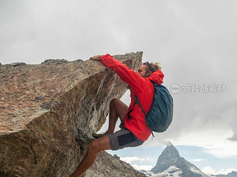 运动健将攀登远处的马特洪峰巨石