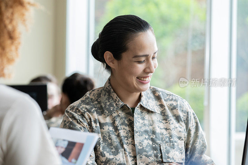 快乐成熟的女兵与年轻新兵一起在办公室工作