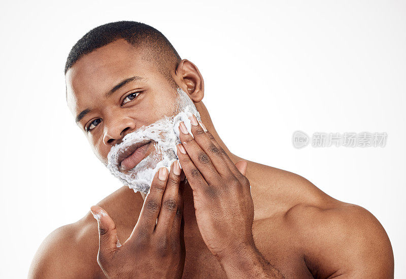 一个英俊的年轻男子在白色背景下把剃须膏涂在脸上的工作室肖像
