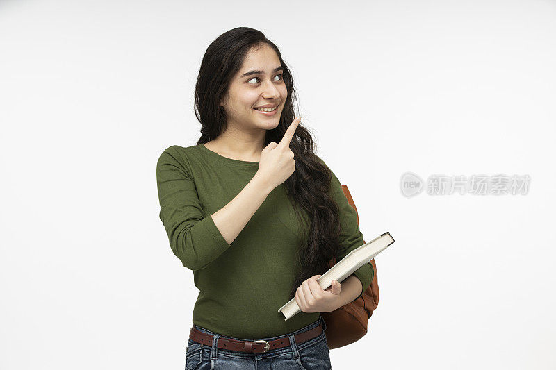 女十几岁的学生背着书包和书微笑的股票照片