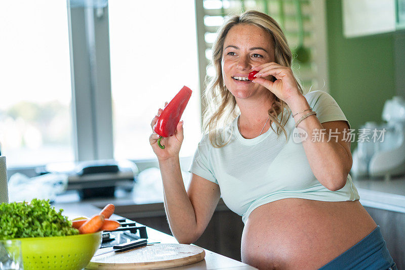 孕妇在厨房里吃蔬菜