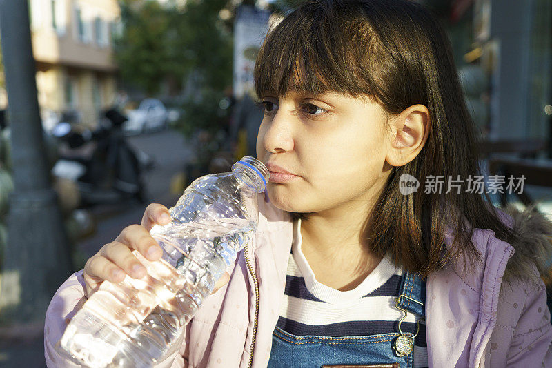 小女孩正在喝瓶子里的水