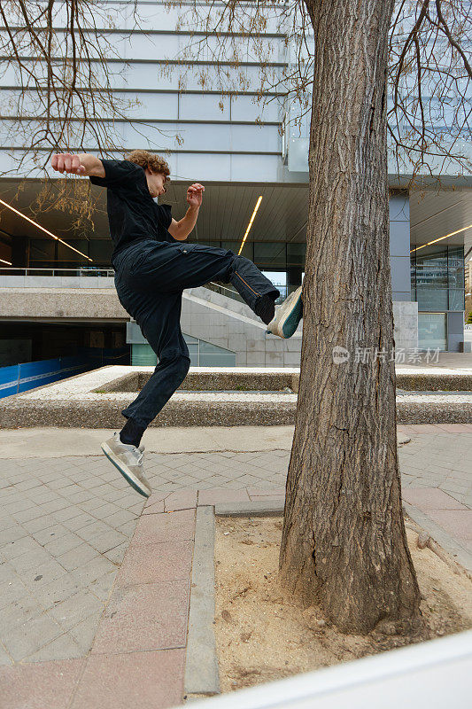 一个年轻的自由奔跑者在城市的一棵树上奔跑跳跃