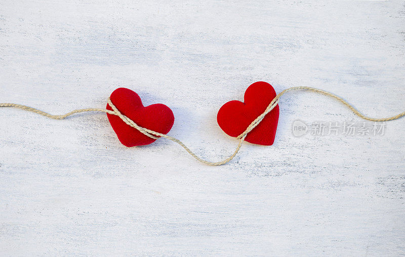 两颗红心用绳子绑在白色桌子的背景上