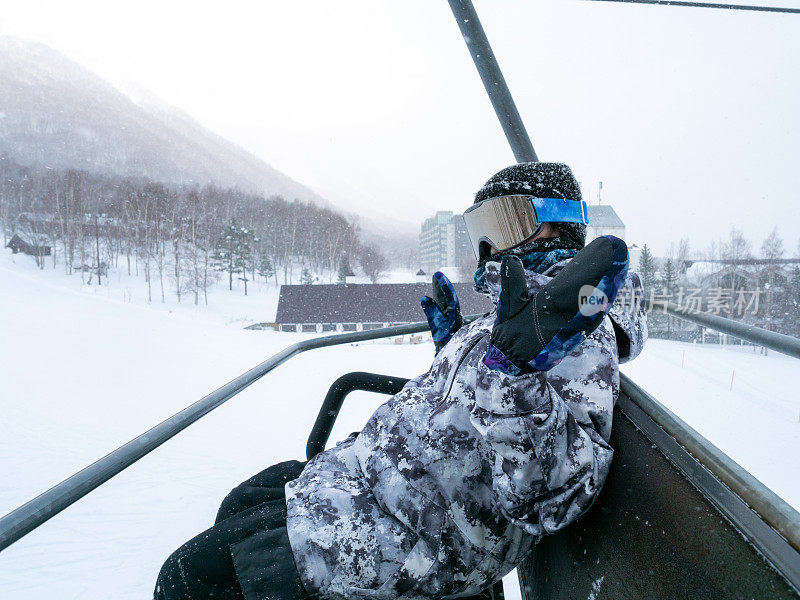 冬天，十几岁的女孩在滑雪缆车上玩滑板