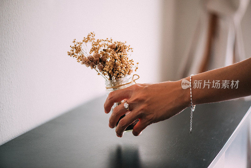 女人们手上戴着钻石戒指，手里拿着玻璃罐里的干花