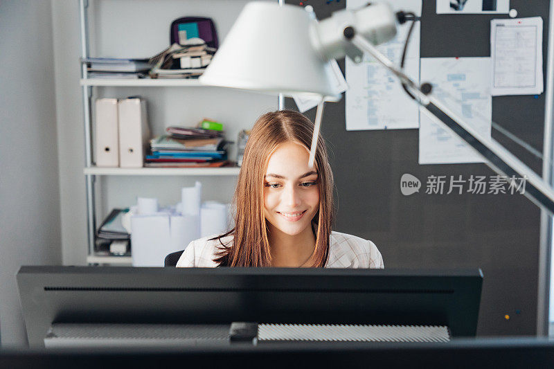 在现代办公室里，女商人在电脑显示屏上阅读电子邮件