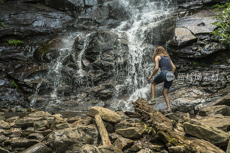 十几岁的女孩在格伦小野子瀑布和小道底部的岩石上攀登，吉姆索普，宾夕法尼亚州。