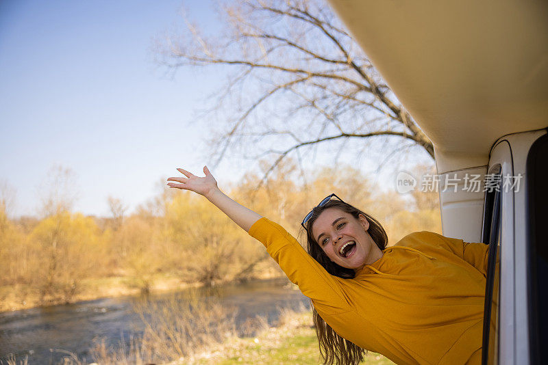 快乐的女人在骑行期间从露营者招手