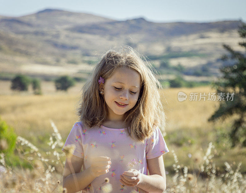 一个金发少女，耳后插着一朵花，站在田野里