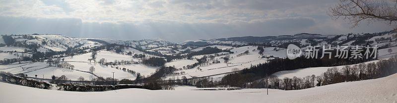 威尔士乡村冬天下雪的场景，暴风雨的天空和阳光穿透云层