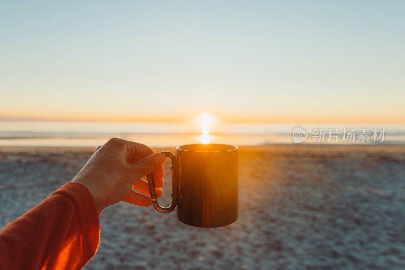 一个女人喝着咖啡，在海边享受着午夜的阳光