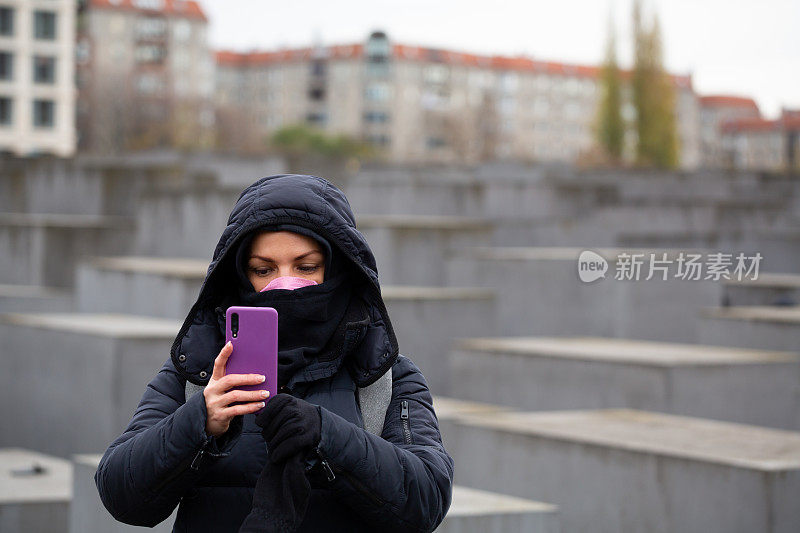 一位女游客在柏林的大街上看她的智能手机
