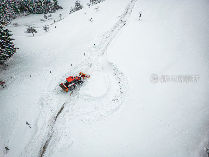 在暴风雪中，一辆红色拖拉机在乡间道路上扫雪