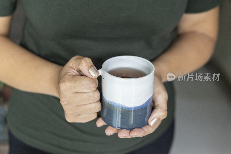 女性手捧陶瓷杯茶