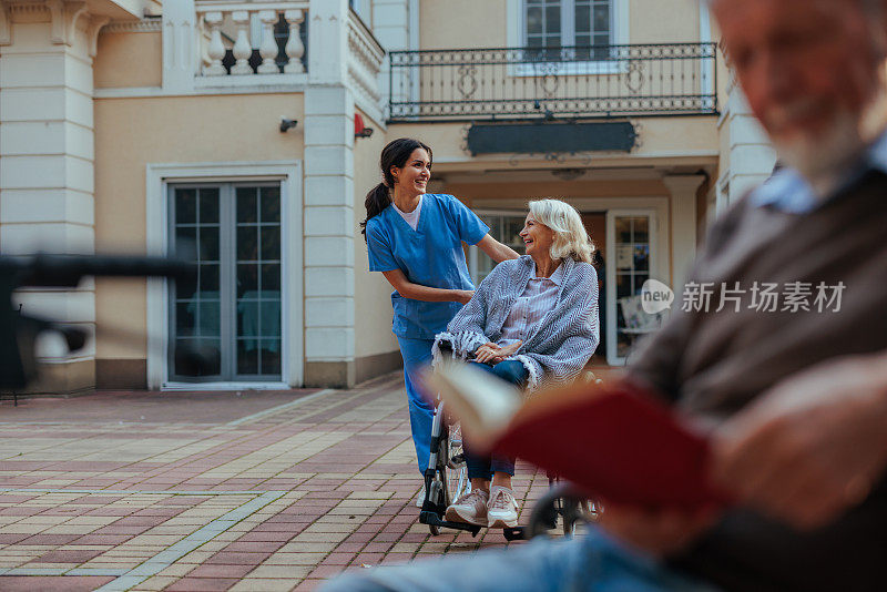 护工与坐在轮椅上的老妇人交谈。