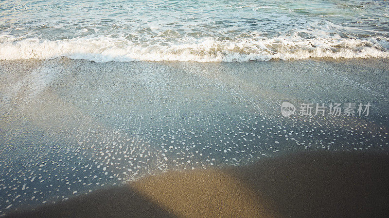 在圣托里尼希腊沙滩上的绿松石海水的软波