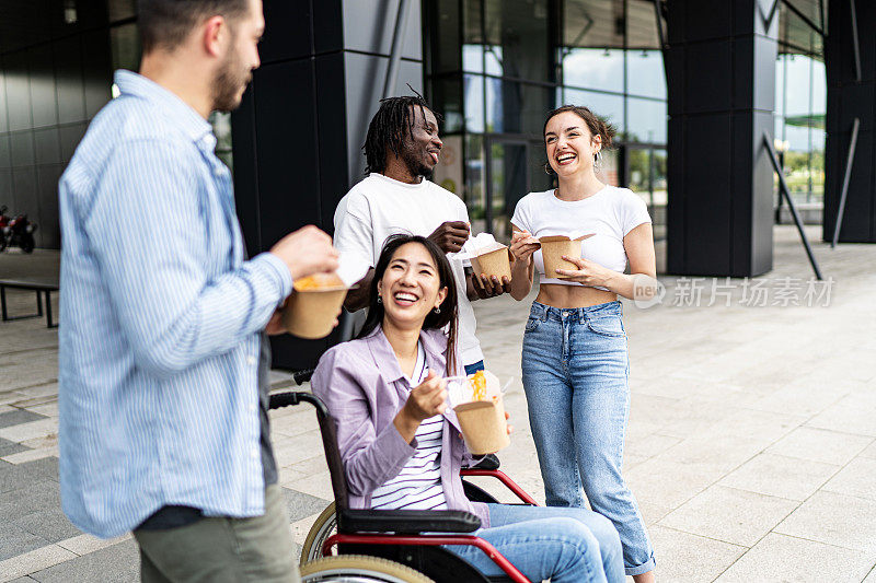 坐在轮椅上的年轻女子在户外和她的朋友们有说有笑。多样性的概念