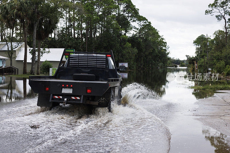暴风雨过后，一辆卡车在被洪水淹没的道路上行驶。飓风过后，北佛罗里达斯坦哈奇居民区