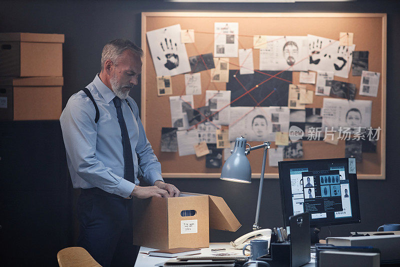 大胡子的高级警探站在办公室里翻看桌上的文件