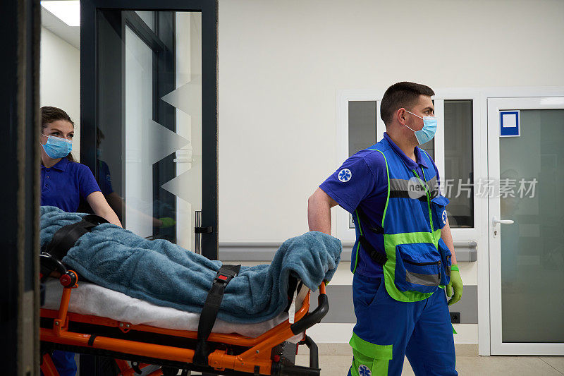医护人员抬着病人的轮床进入医院走廊