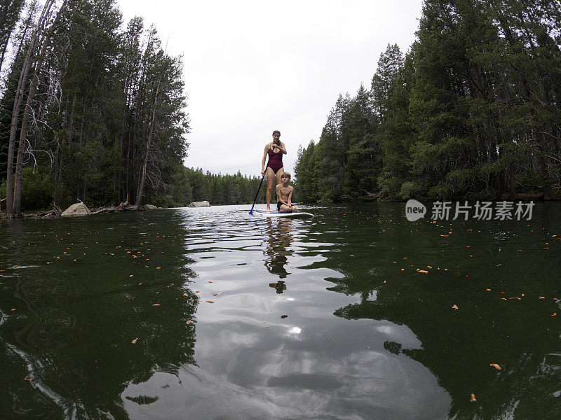 母亲和孩子们在湖上玩桨板