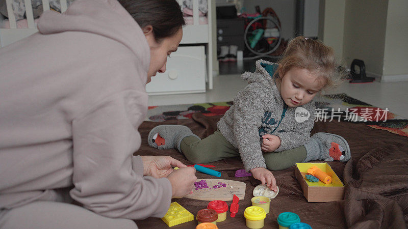 妈妈和孩子在家里玩橡皮泥。家庭时间。