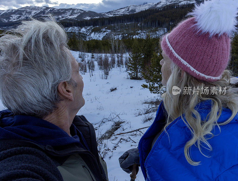 成熟的夫妇在白雪皑皑的冬天徒步旅行