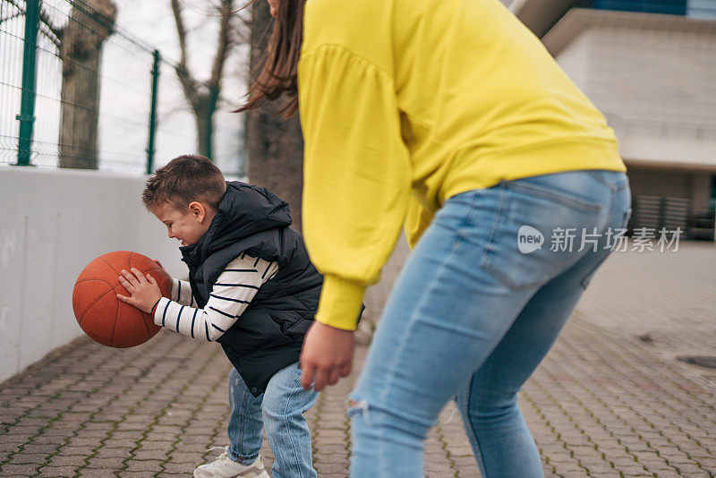 母亲和儿子一起在户外打篮球。