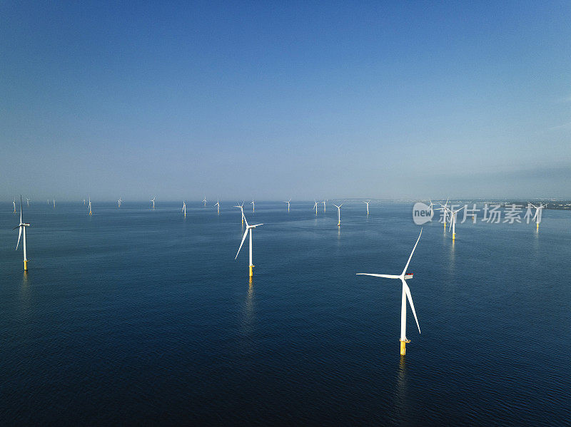 海上风力发电装置雄伟地矗立在海上，一排排的涡轮机利用风力产生可再生能源。