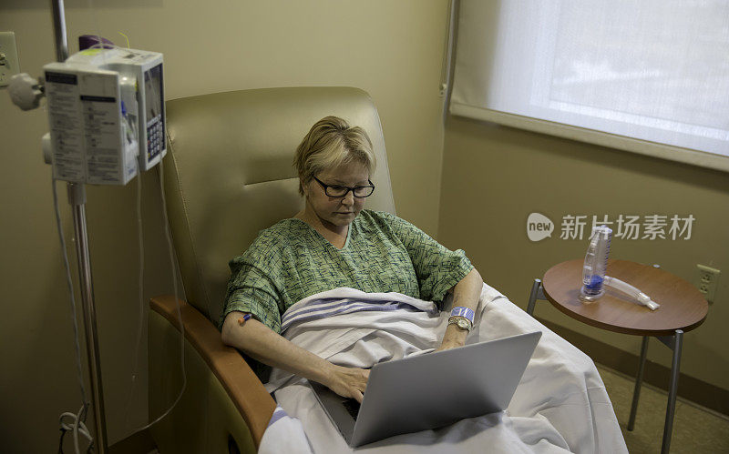 女病人坐在病房的椅子上用笔记本电脑工作