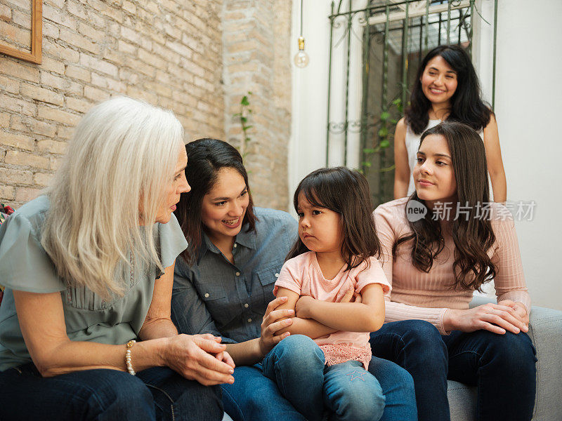 小墨西哥女孩和墨西哥女人坐在一起皱着眉头