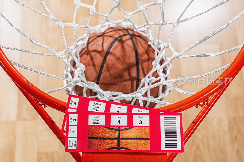 看着两张篮球球票，一个球穿过球网，背景是球场的木地板