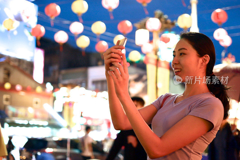 年轻女子在夜市拍照