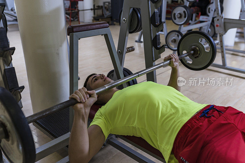 一位年轻的健美运动员正在健身房做举重锻炼