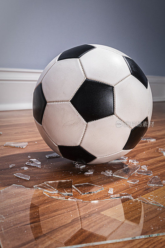 地板上的一个带有破碎玻璃的足球