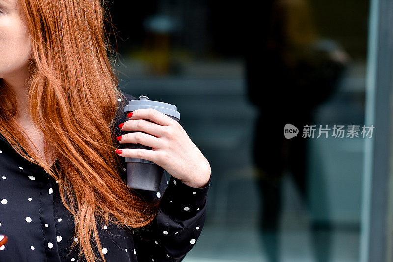 红头发的女人拿着可重复使用的可持续旅游杯