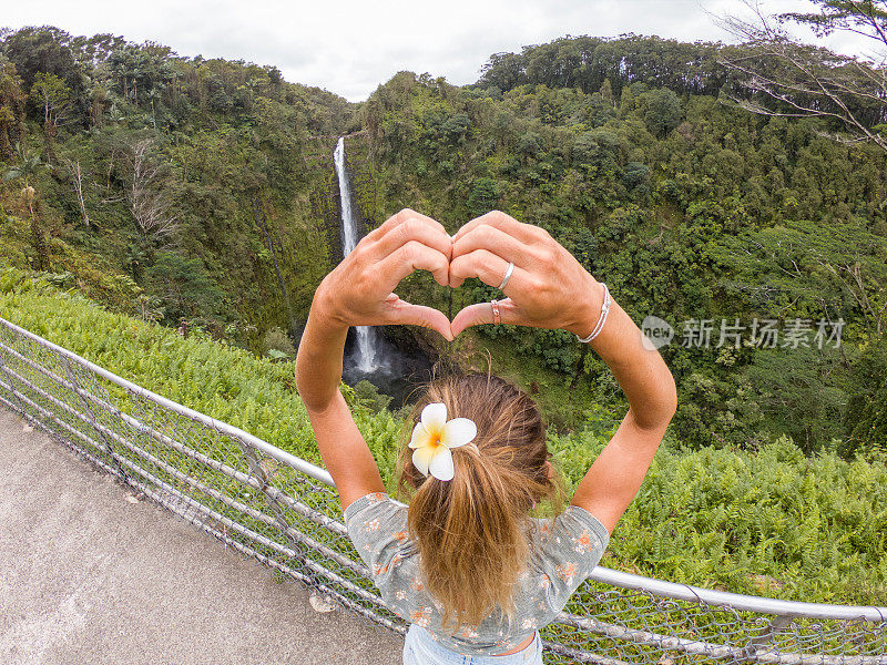 在夏威夷瀑布上做心形图案的女人
