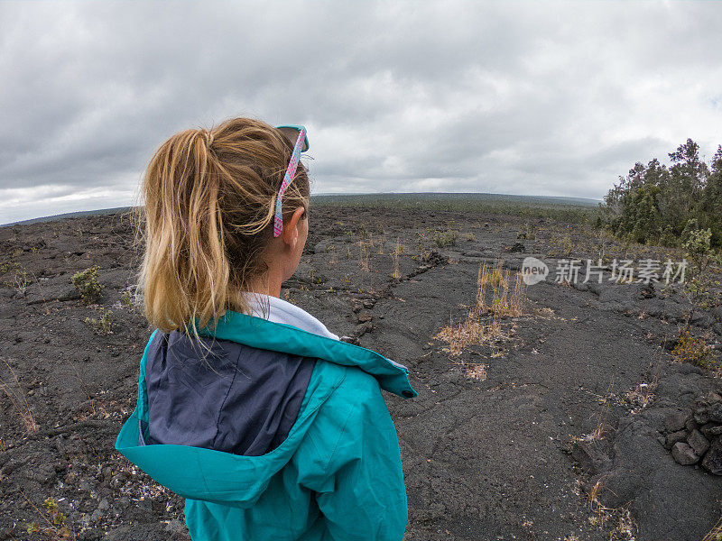 一名年轻女子站在夏威夷火山国家公园的熔岩上