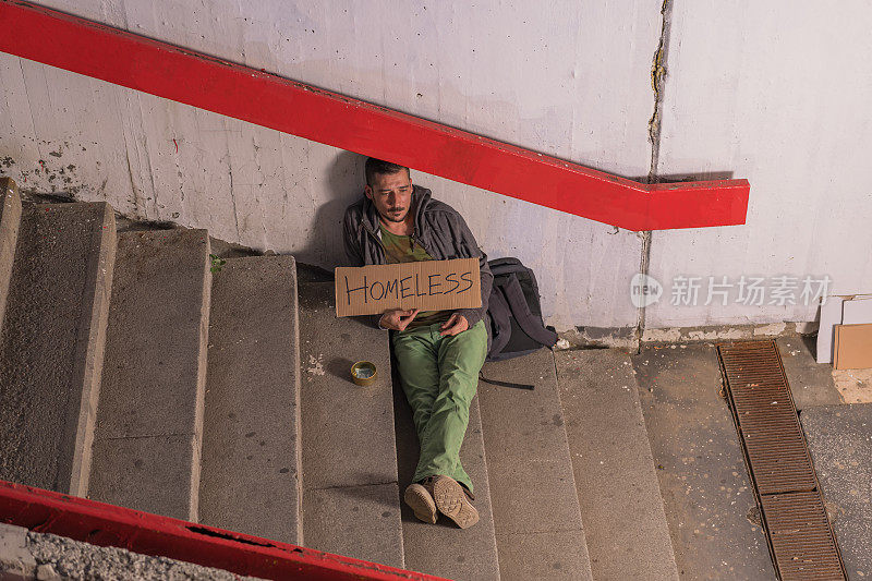 无家可归的乞丐坐在城市的地下等待捐赠