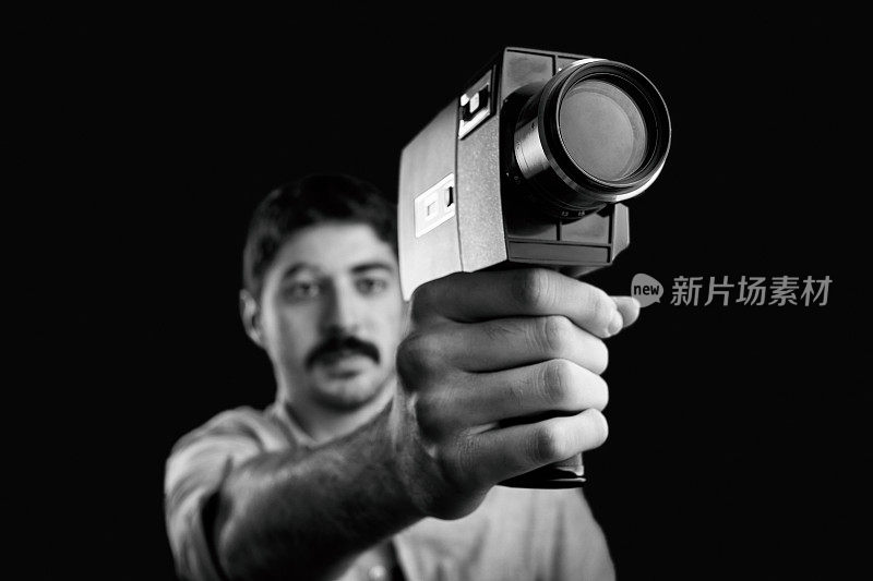 用老式摄影机拍摄的年轻电影摄影师。把相机对准枪。