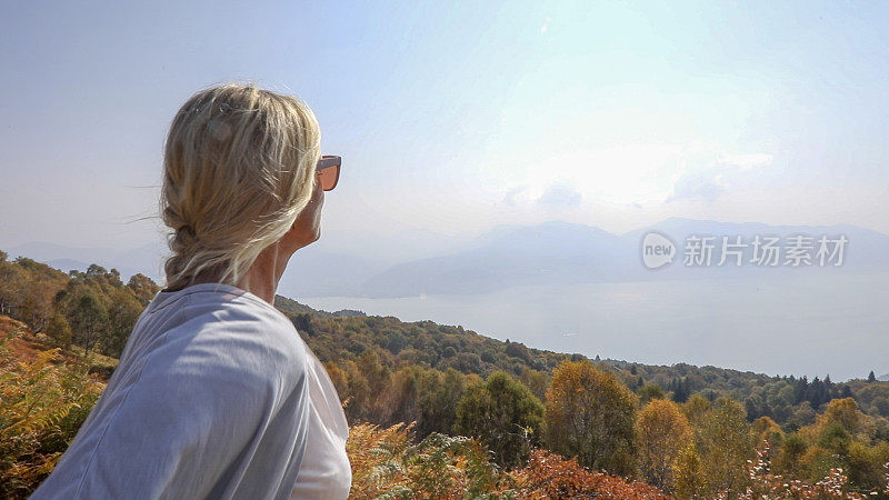 成熟的女人在秋天探索山中的山坡