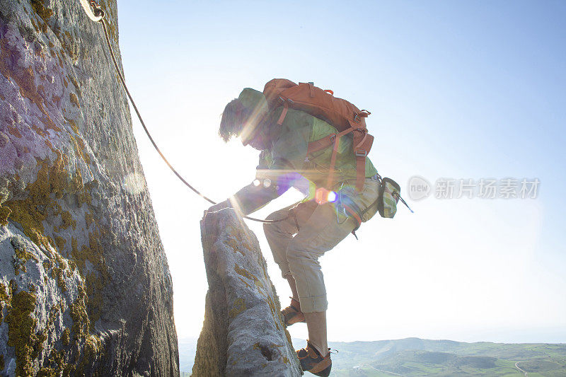 登山者在日出时攀登岩面