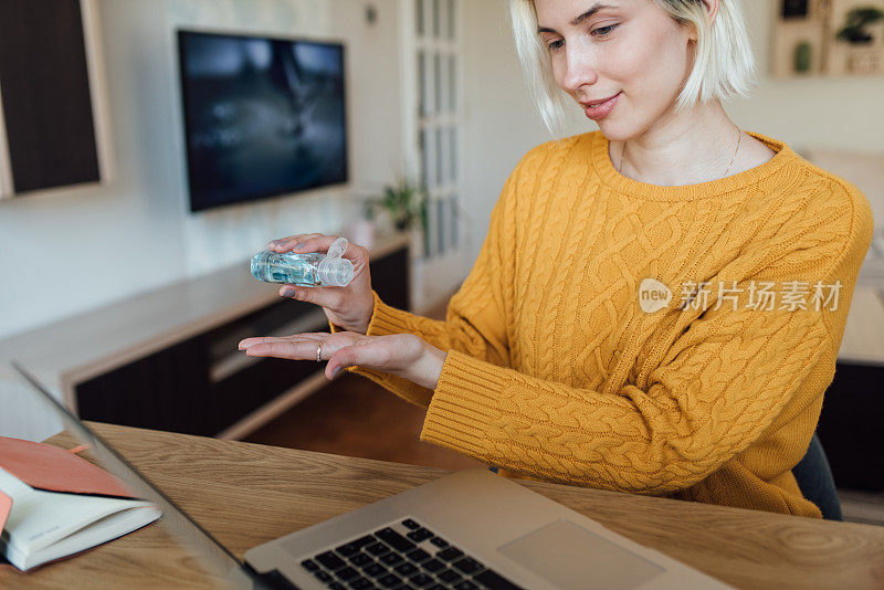 女孩在使用手提电脑前要消毒双手